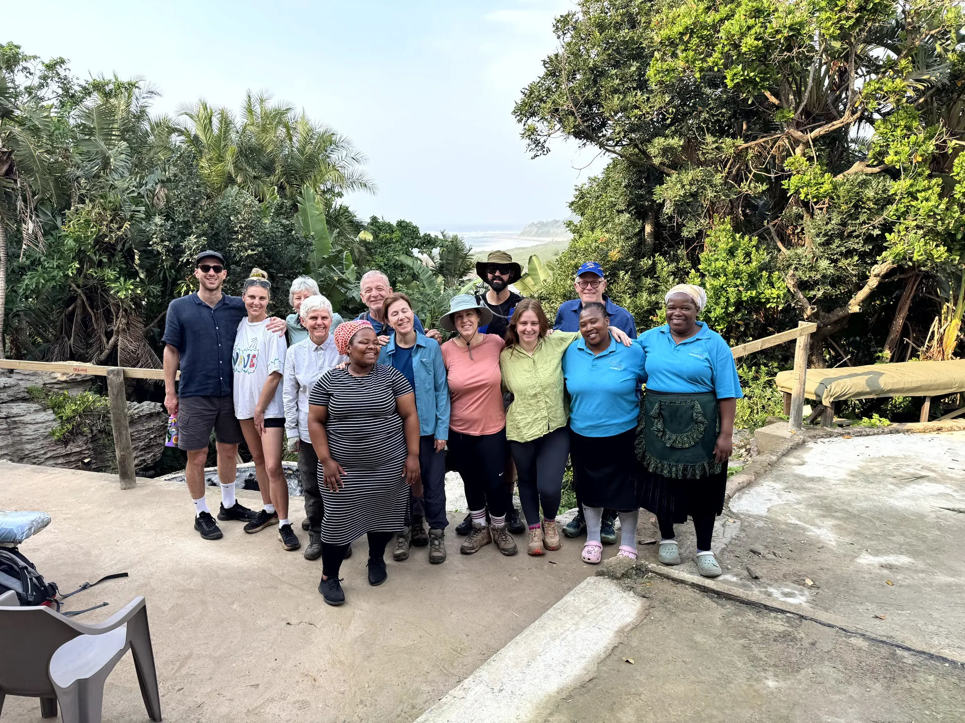 Group photo of hikers and local hosts at tropical lodge