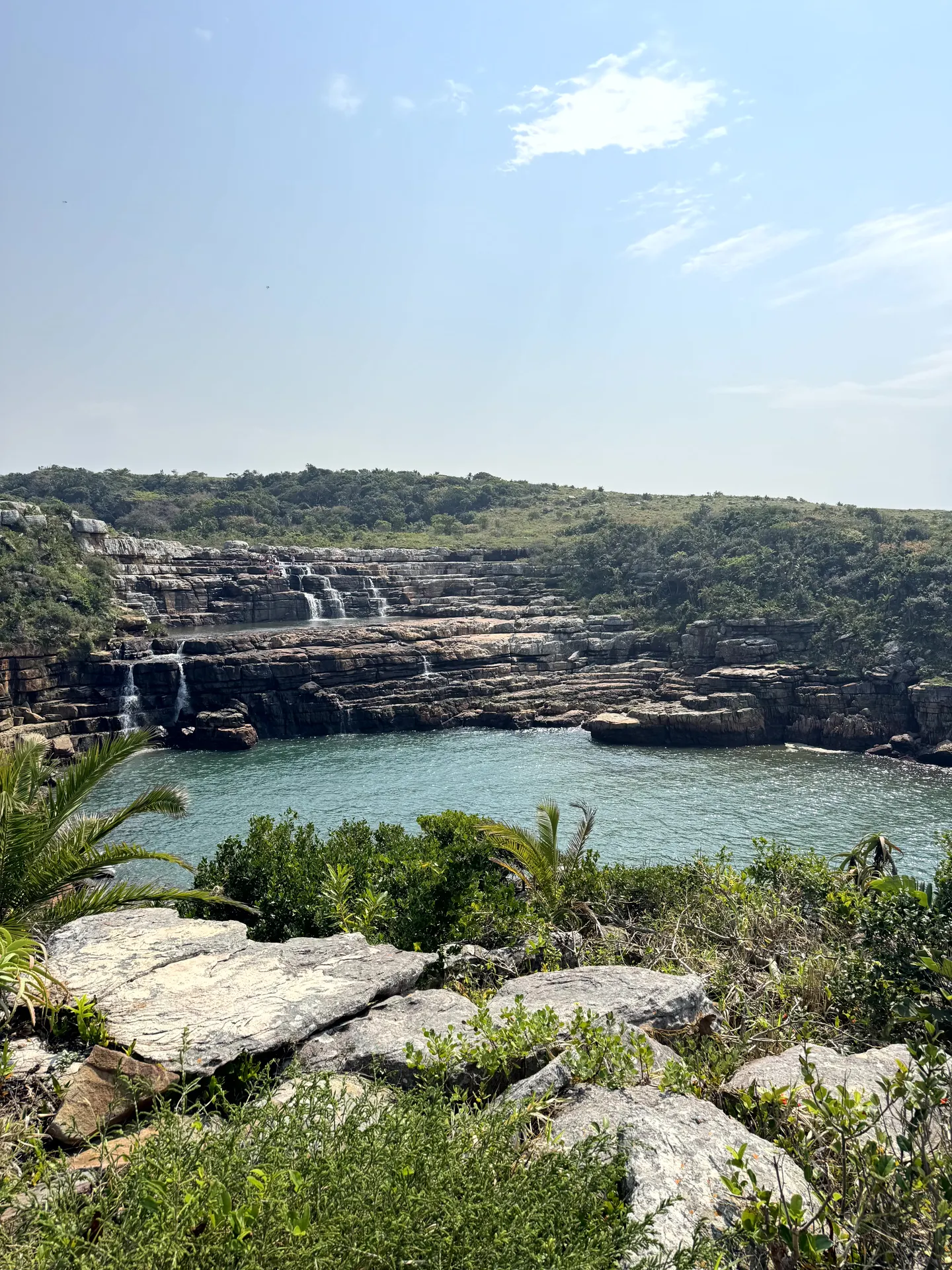 Cascading waterfalls flowing into turquoise pool surrounded by rocky cliffs