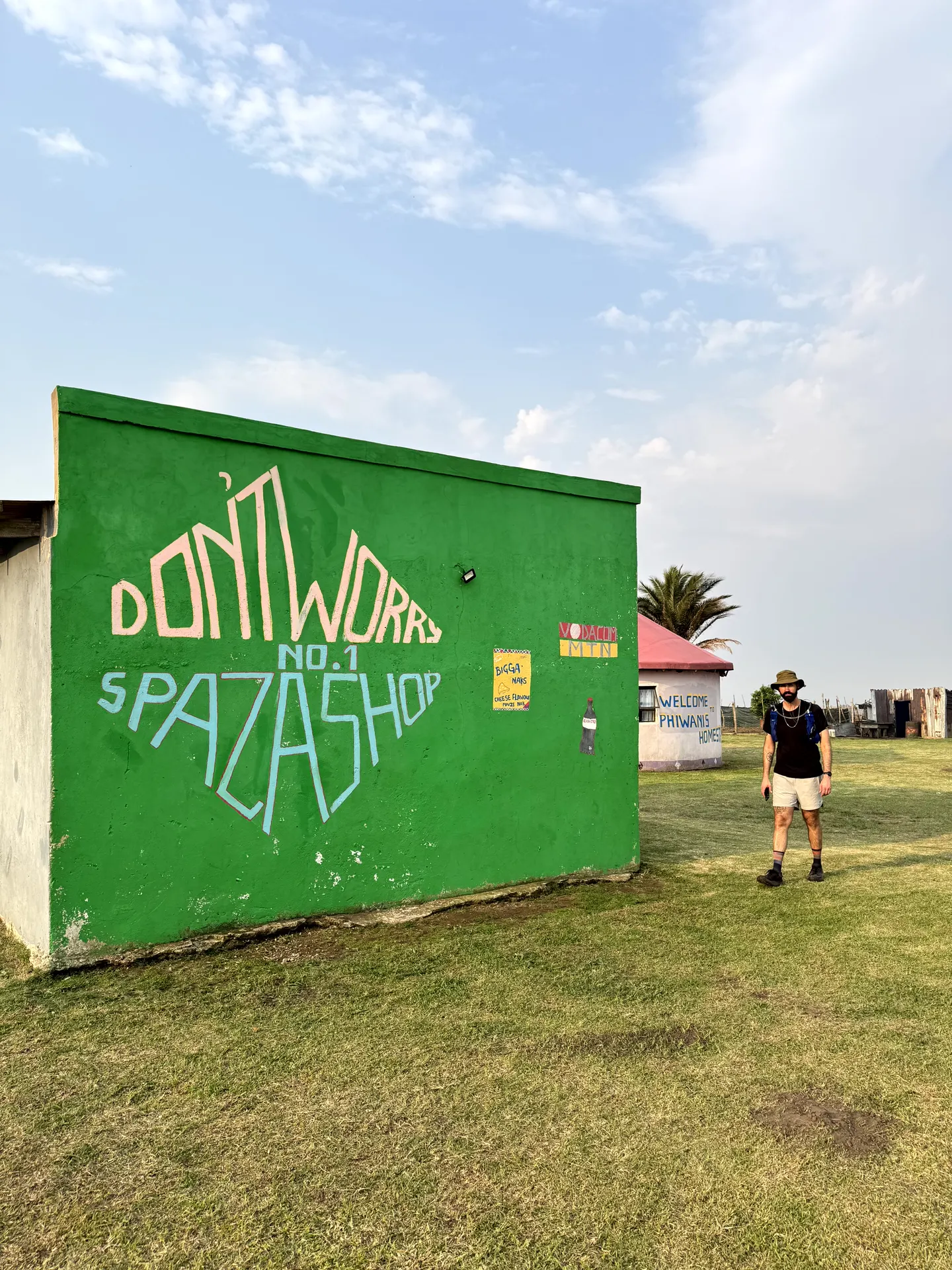 Don't Worry Spaza Shop with vibrant green wall and hiker