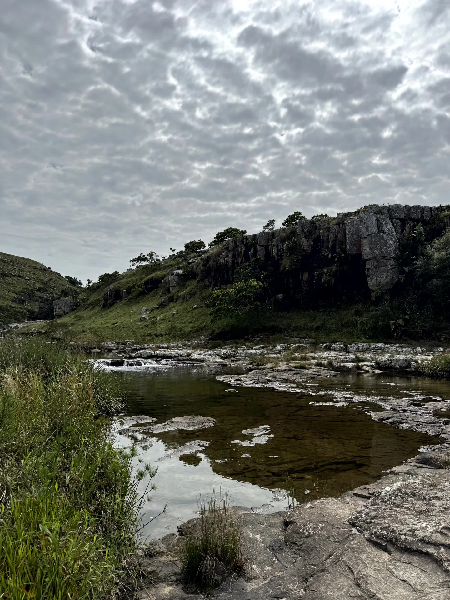 Rocky stream with dramatic cliff formation and textured clouds